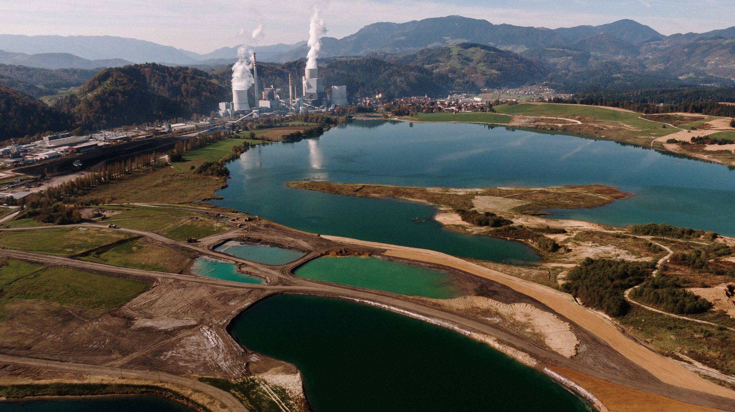 An aerial shot of a landscape surrounded by mountains and lakes with industrial disaster