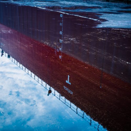 Reflection of building in puddle on street.