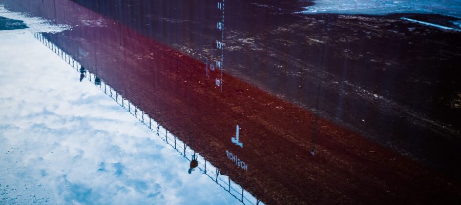 Reflection of building in puddle on street.